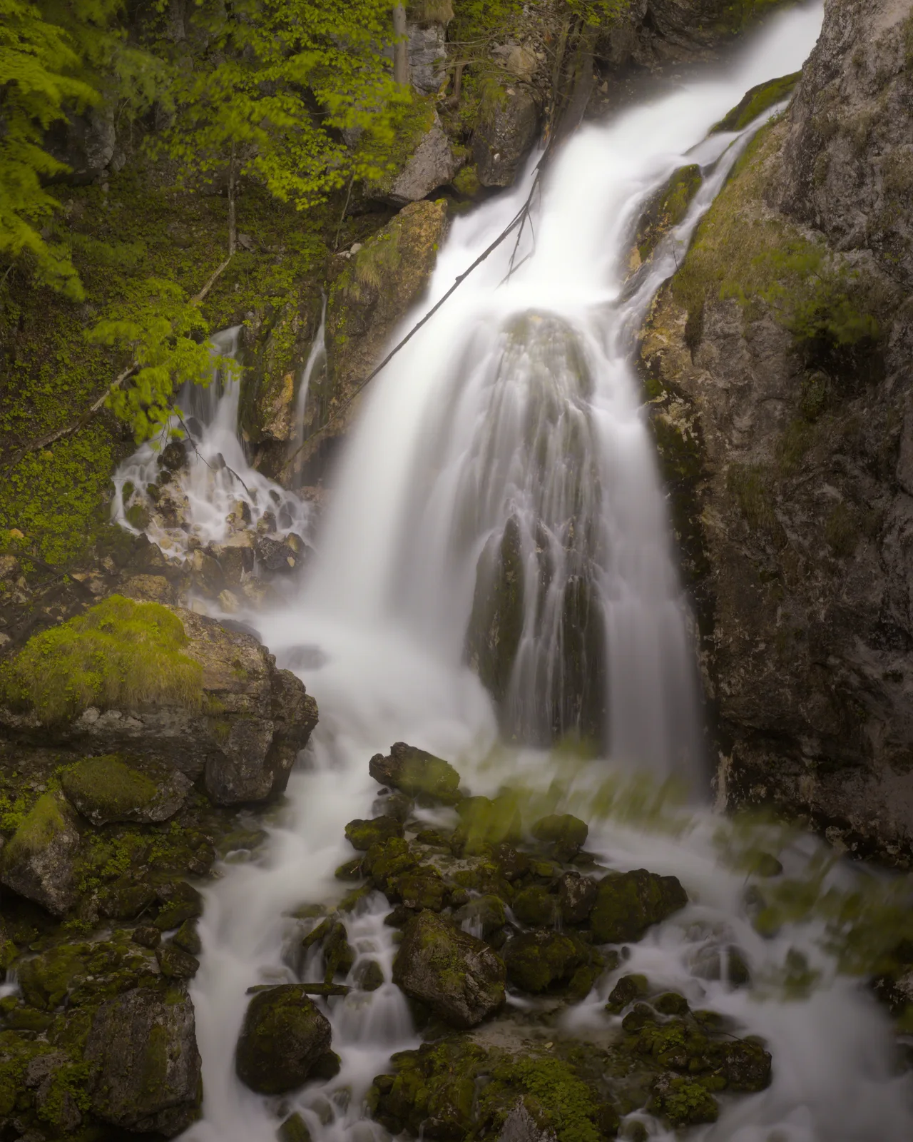 Ein mehrstufiger Wasserfall stürzt über bemooste Felsen in